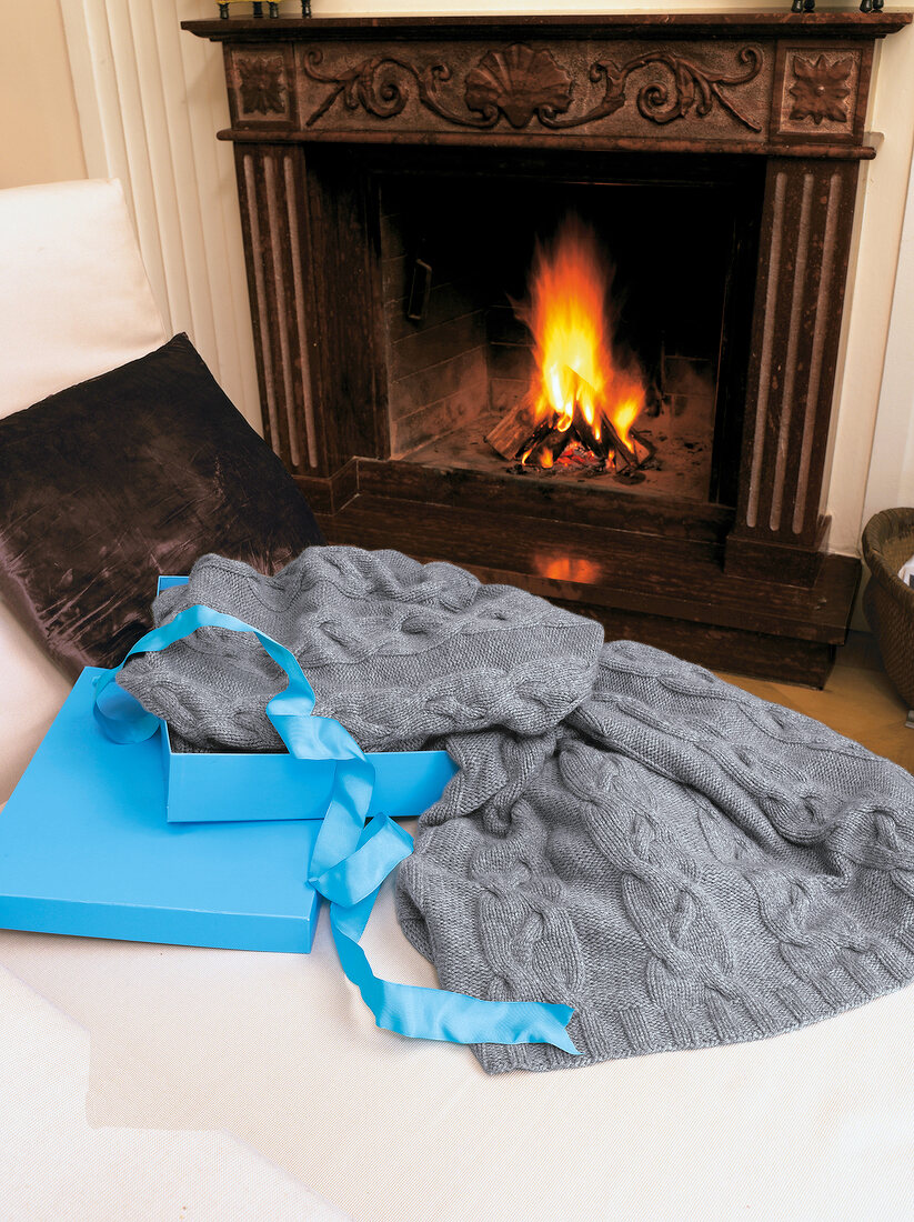 Cashmere blanket with cable pattern against burning fireplace