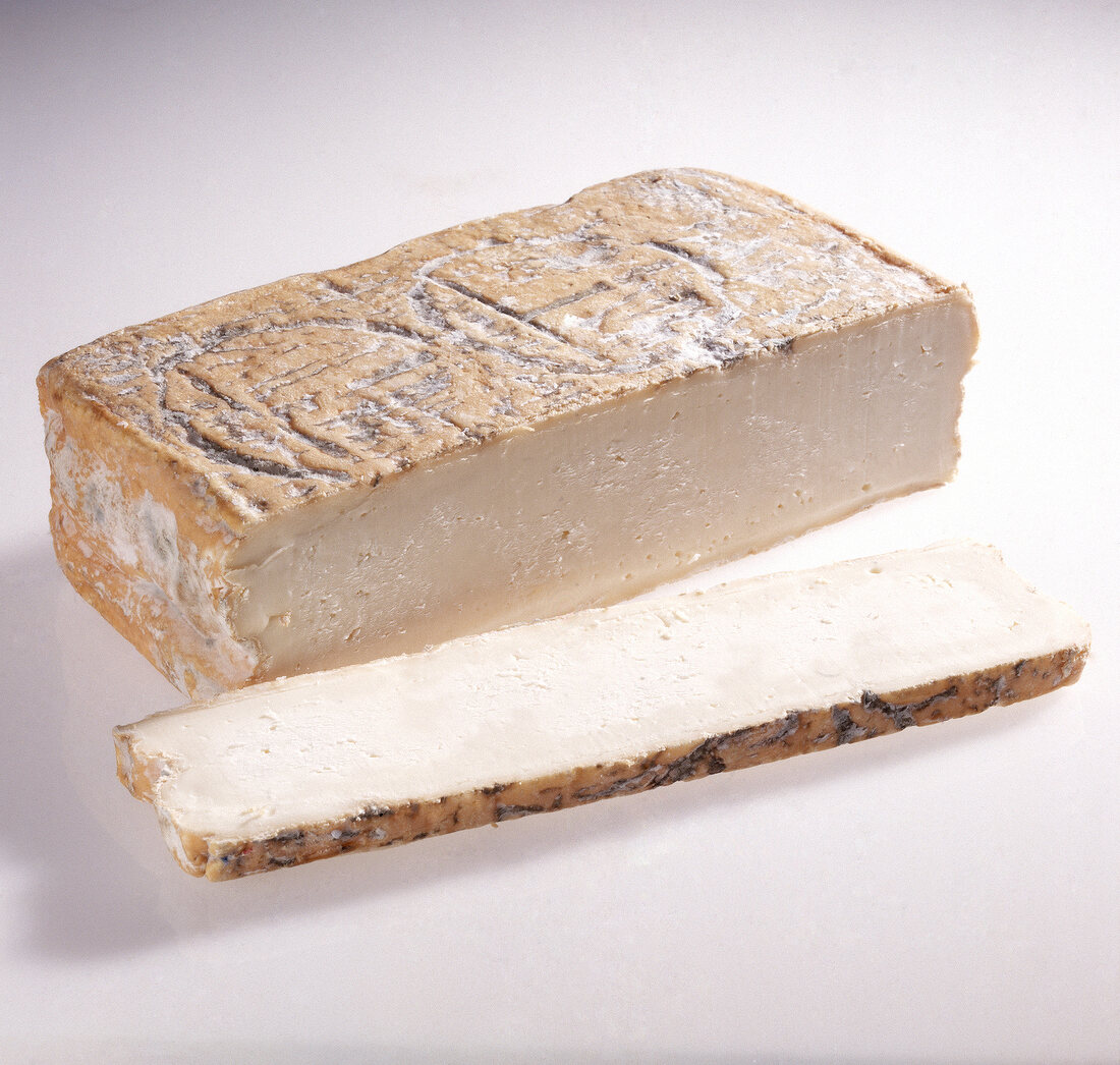 Taleggio cheese and one slice of it on white background