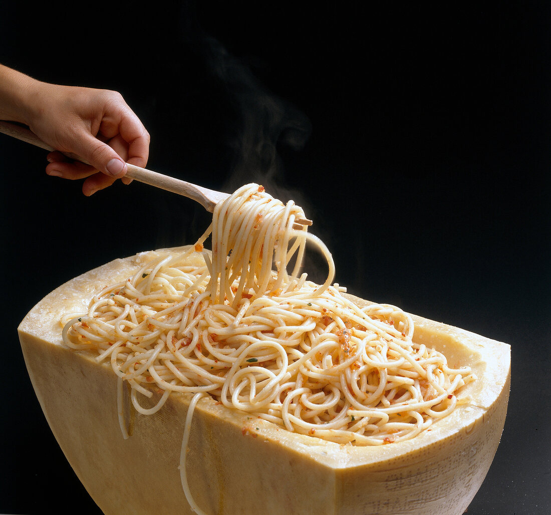 Hand holding fork with noodles in parmesan cheese, step 5