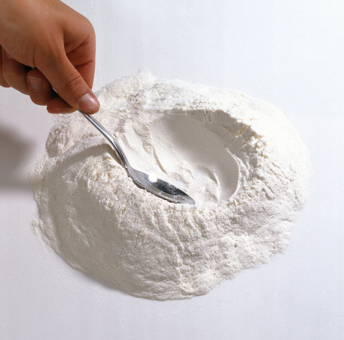 Flour being spread with spoon while preparing pasta, step 1