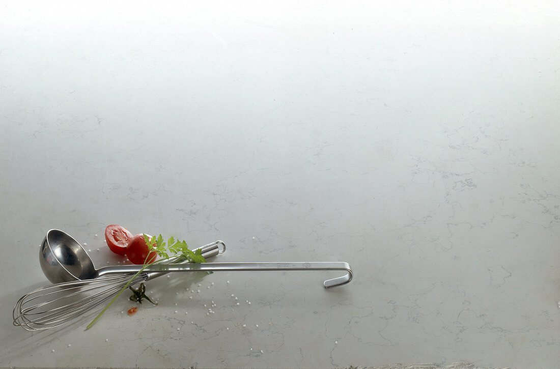 Ladle, whisk eggs, herbs and halved tomato on white background, copy space