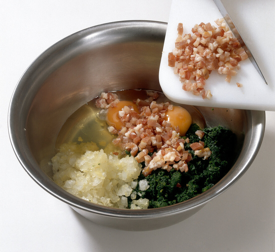 Ingredients for stuffing being added in steel bowl for preparation of dumpling, step 2