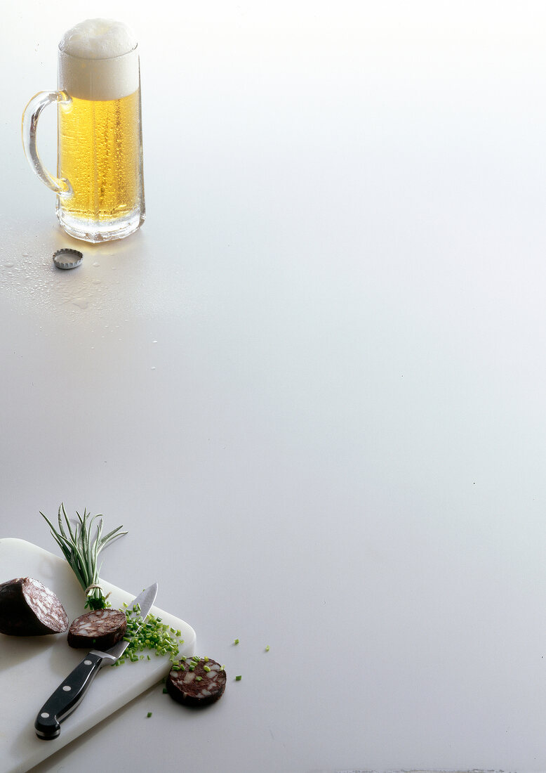 Blood sausage and chives on cutting board and glass of beer on white background