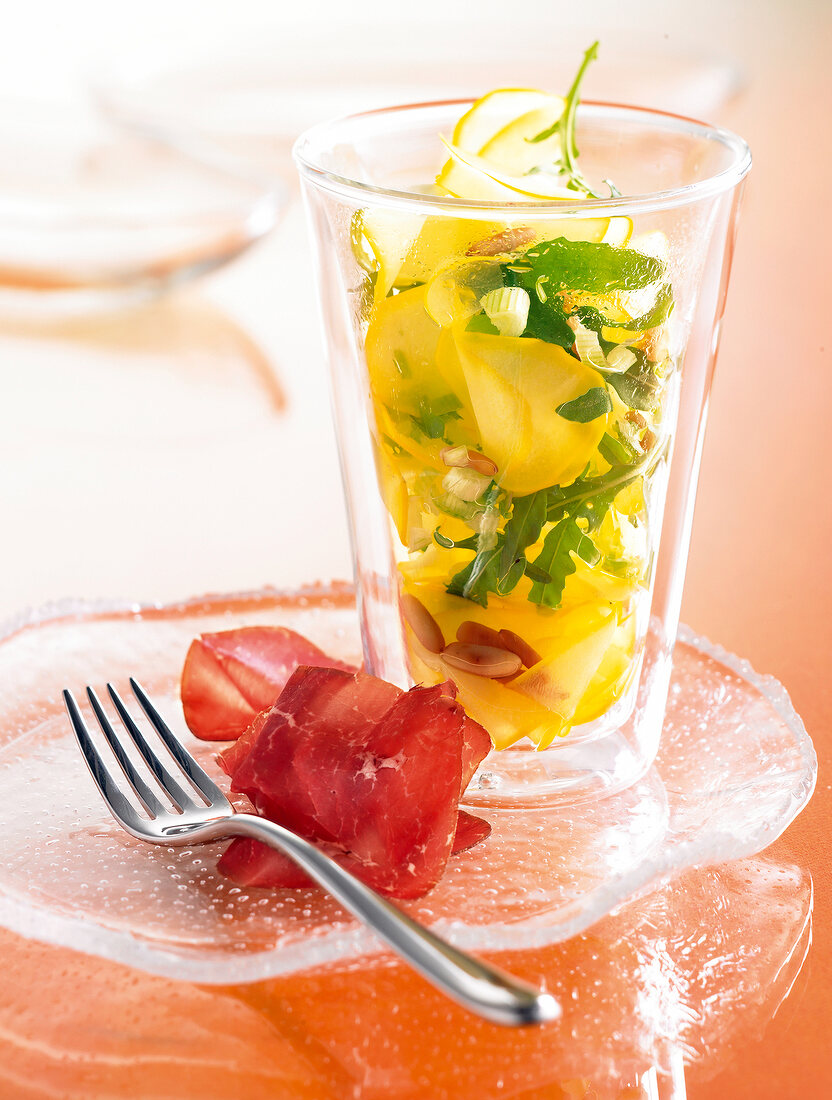 Glass of zucchini and rocket leaves salad on glass plate