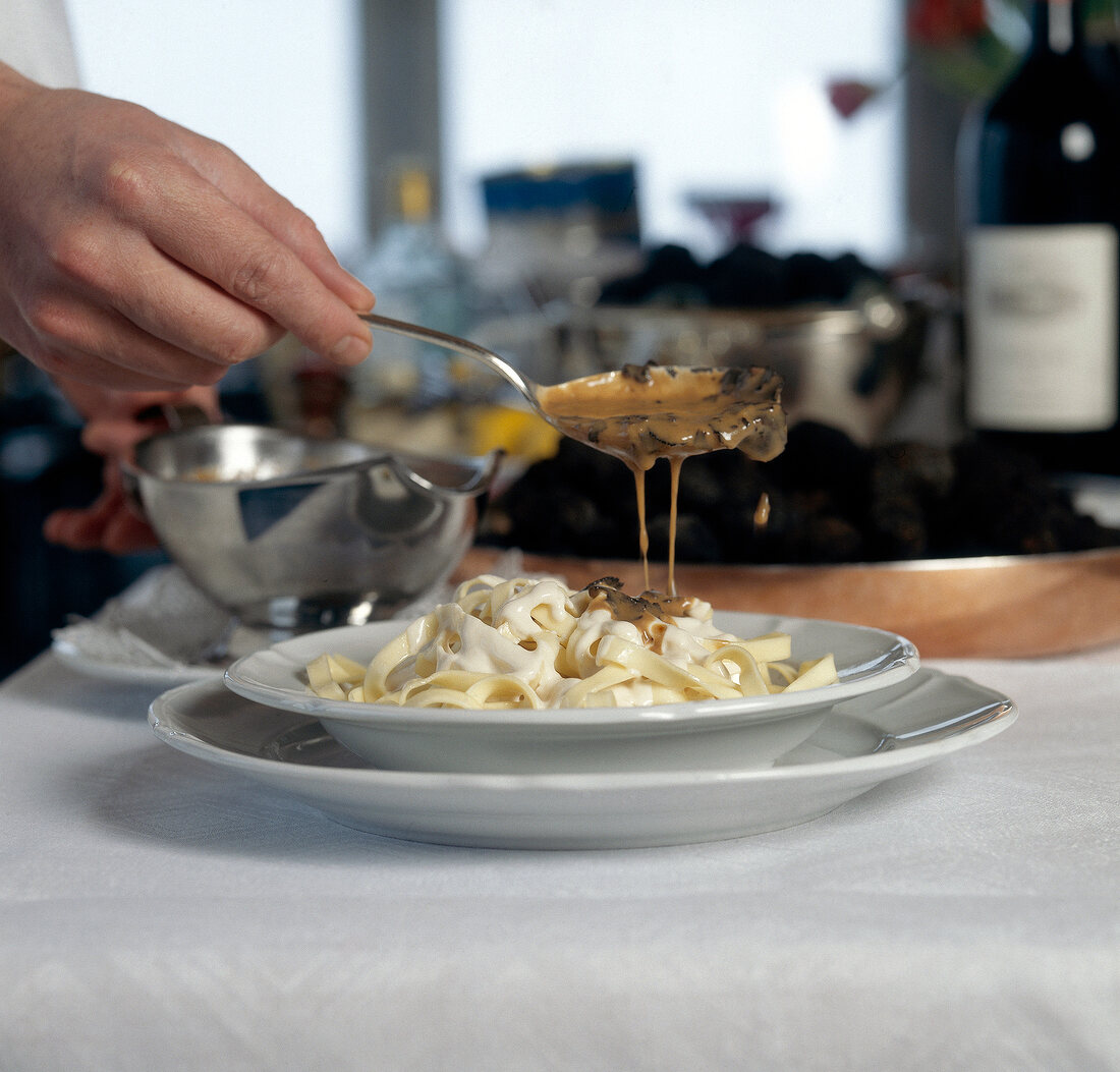 Perigord sauce being poured over pasta while preparing tagliatelle alla mathis, step 2