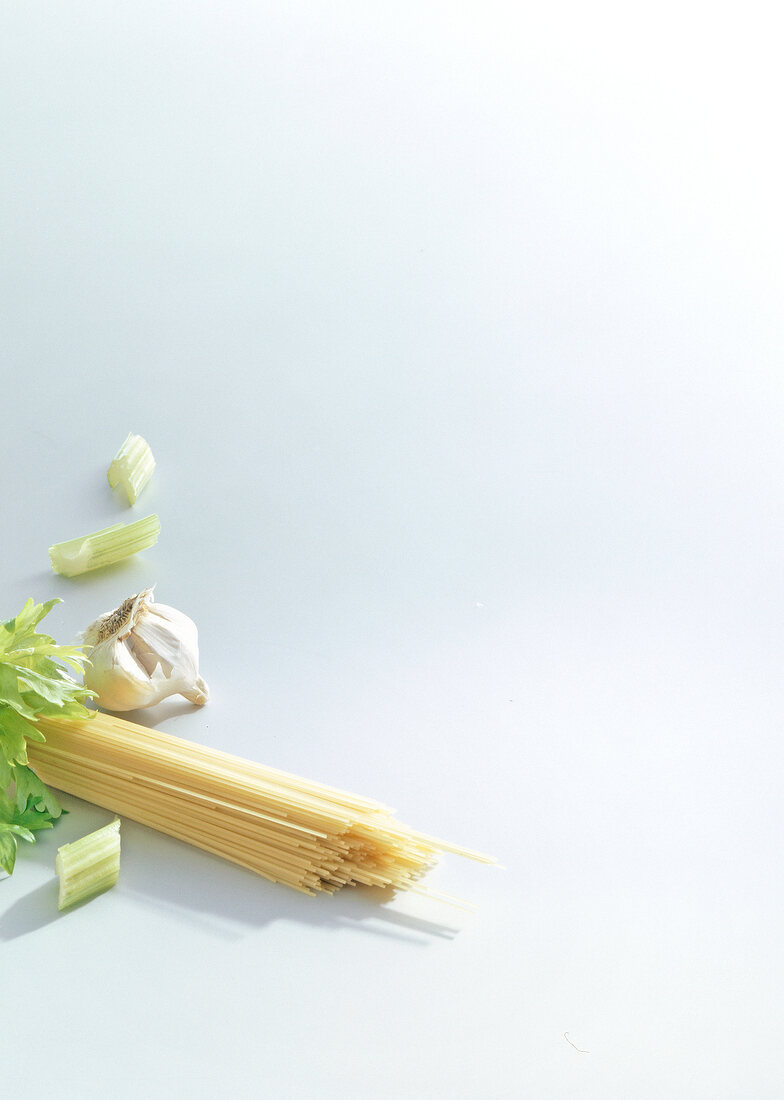 Raw spaghetti and garlic on white background
