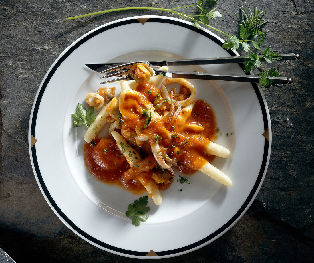 Potato noodles with tomato and seafood on plate