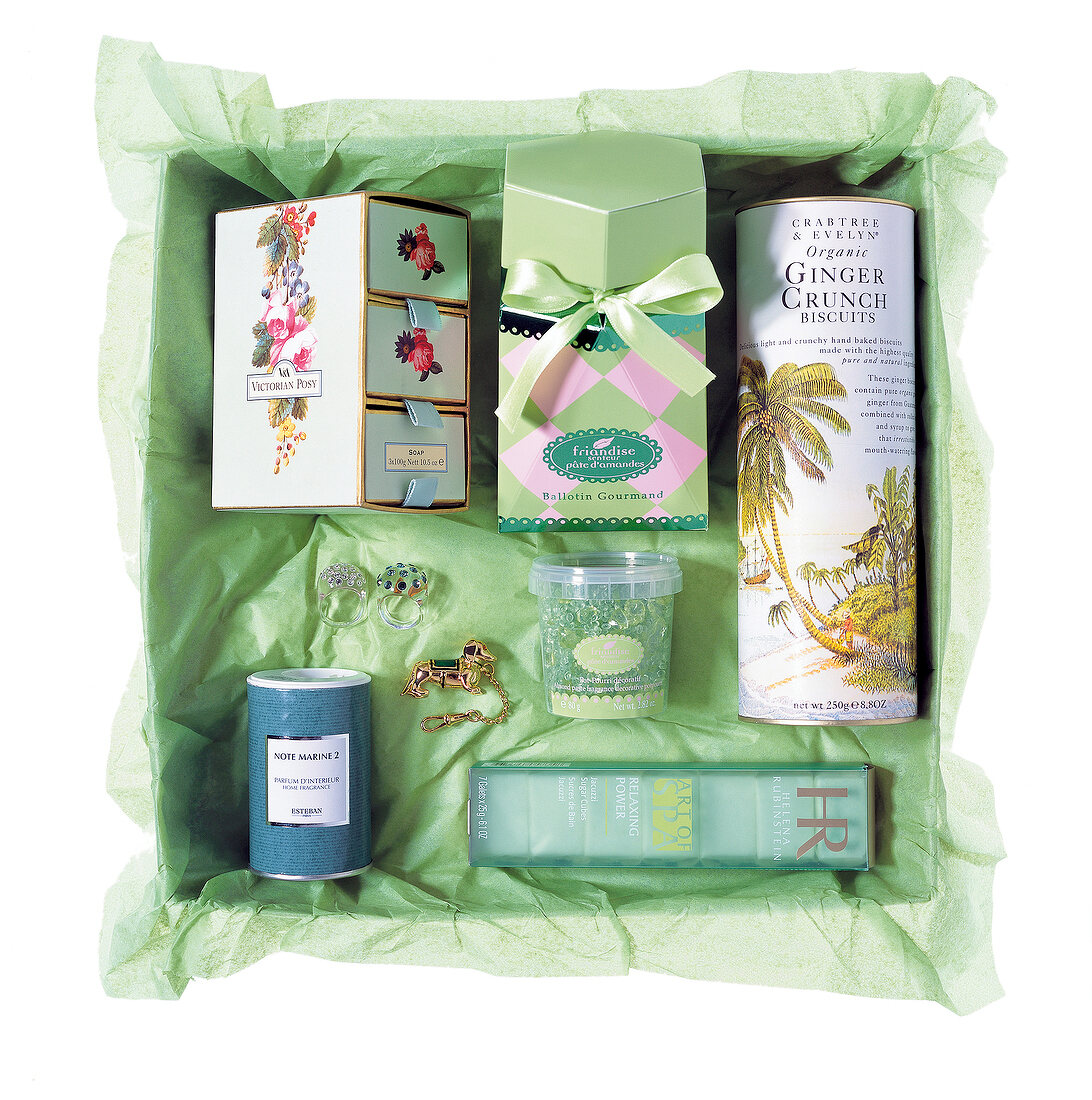 Geschenk-Sortiment: Beauty-Produkte auf gruenem Seidenpapier