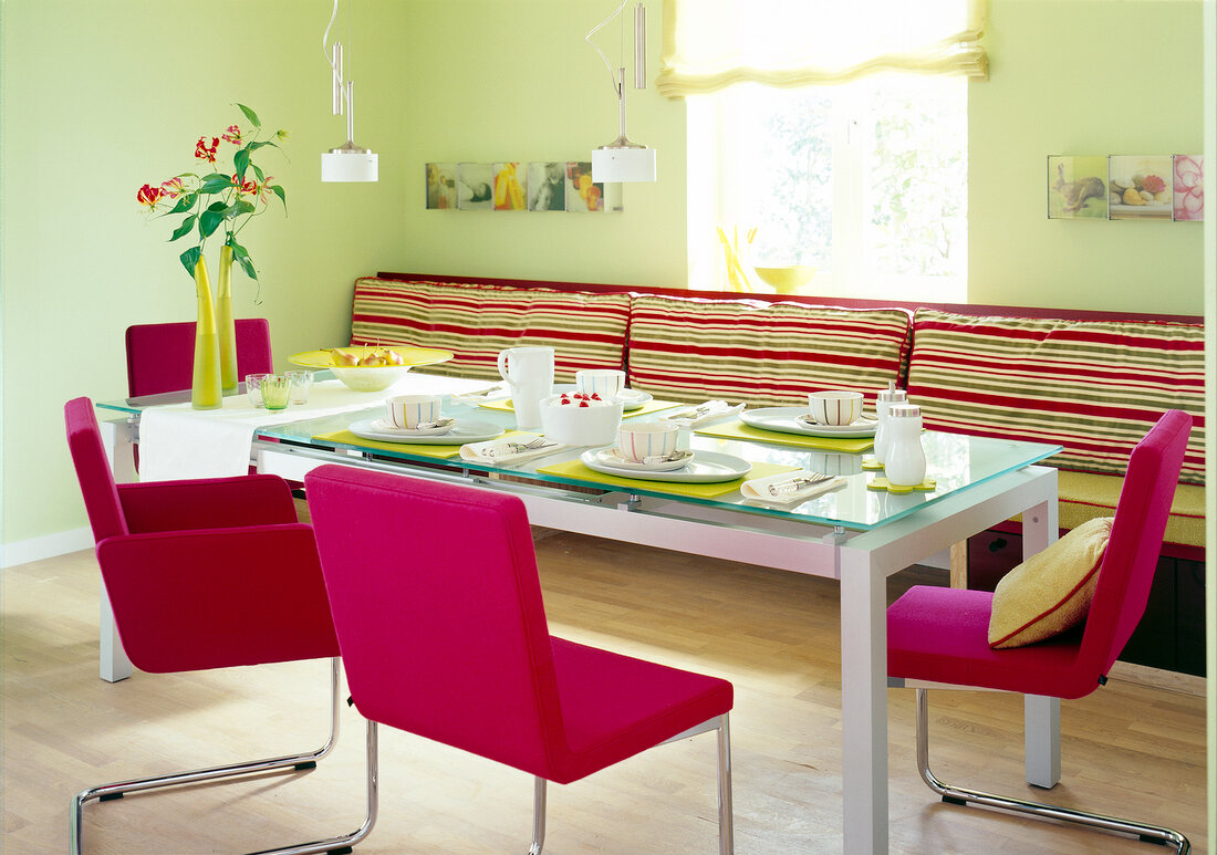 Laid dining table with pink chairs, seat with striped upholstered and green walls