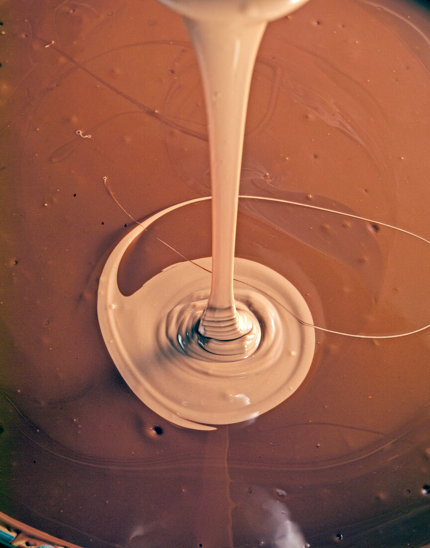 Close-up of liquid chocolate being poured in melted dark chocolate, book of chocolate