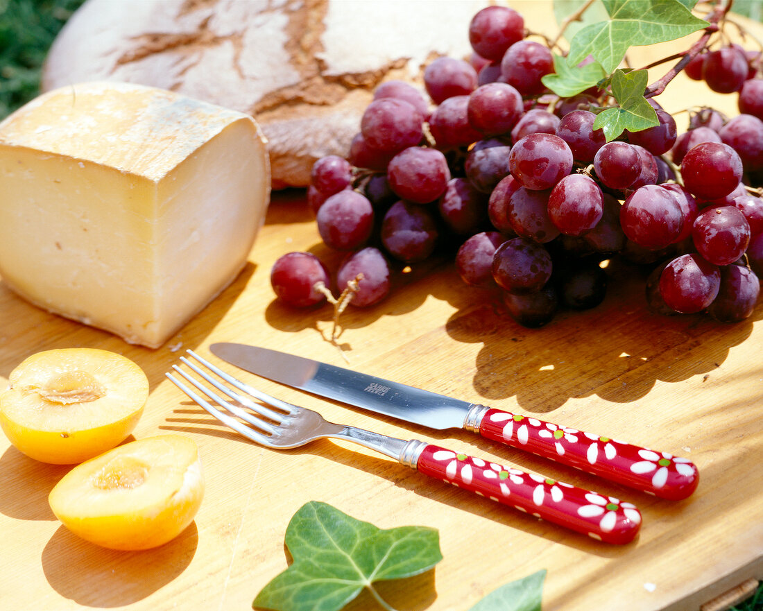 Brot, Käse, Weintrauben und zwei Pfirsichhälften