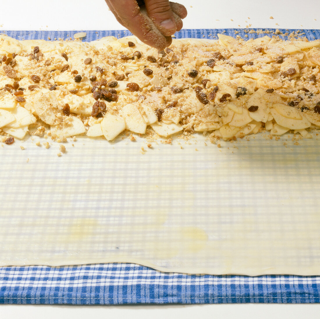 Toasted breadcrumbs and nuts topped on greased dough sheet for preparing strudel