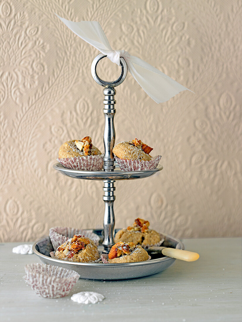 Walnut balls with date marzipan filling on steel tiered stand against wall