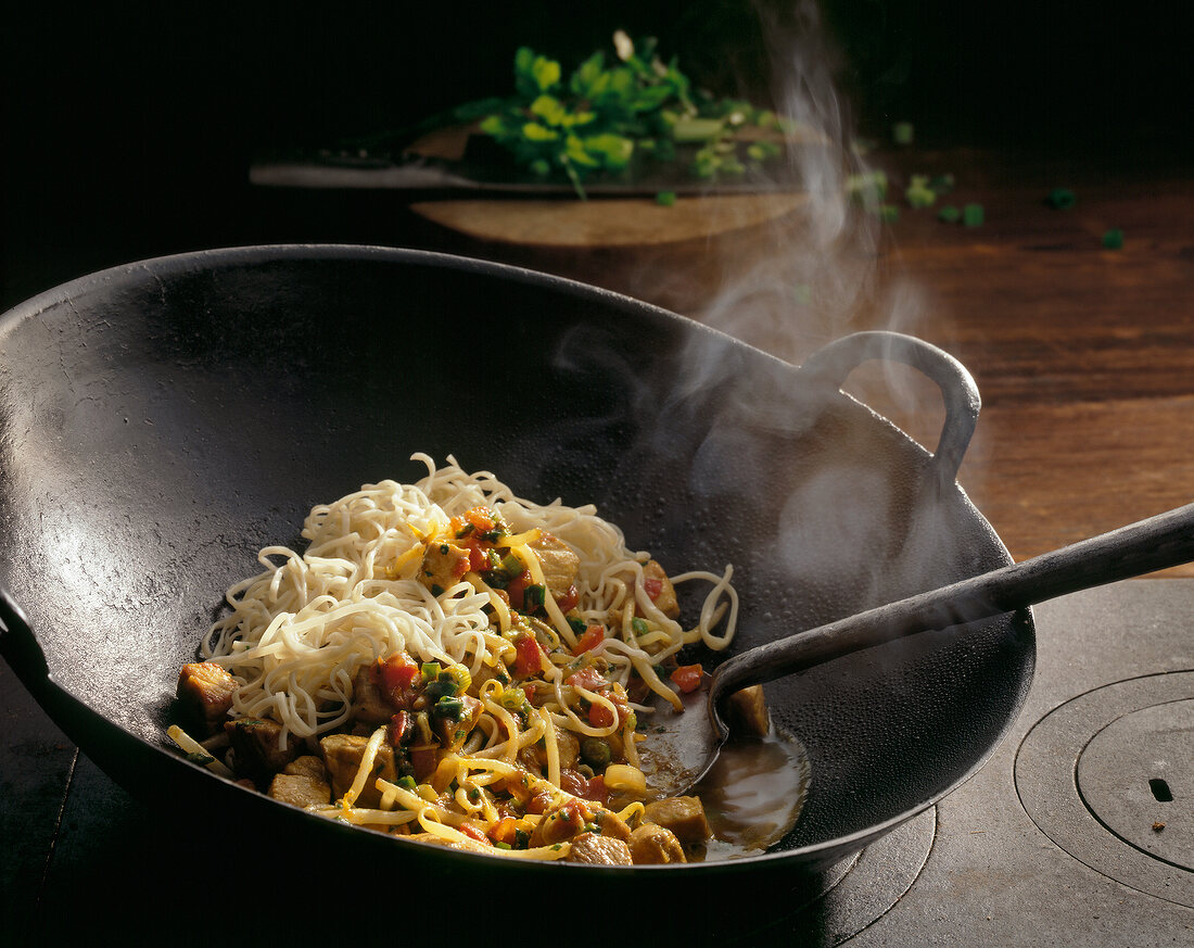 Egg noodles with pork being cooked in pan