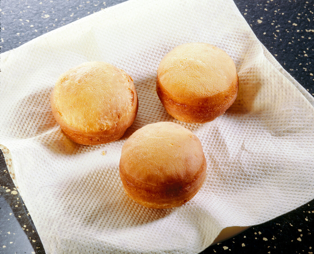 Three brown fried buns kept on tissue paper to drain and get cool