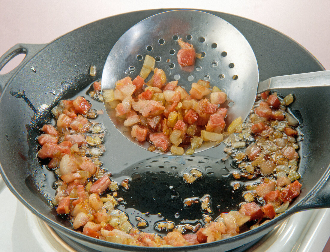 Fried bacon with onion cubes and oil in pan