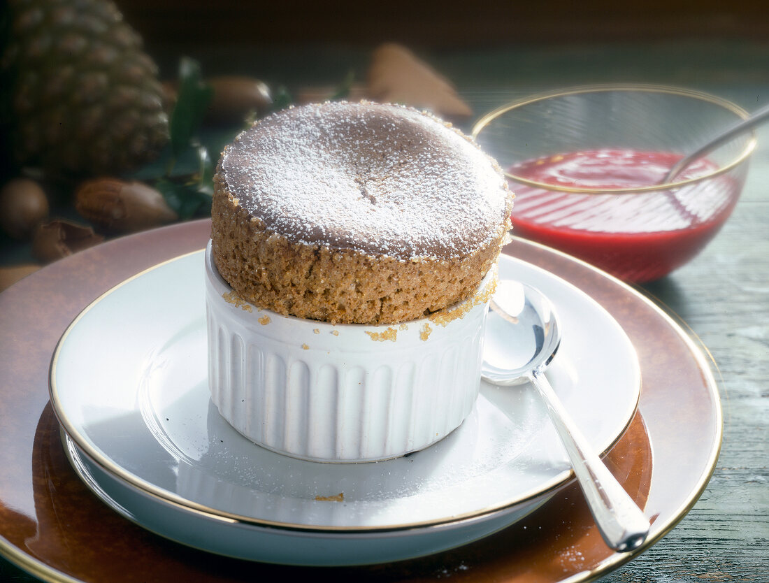 Gingerbread souffle in ramekin with bowl of cranberry sauce