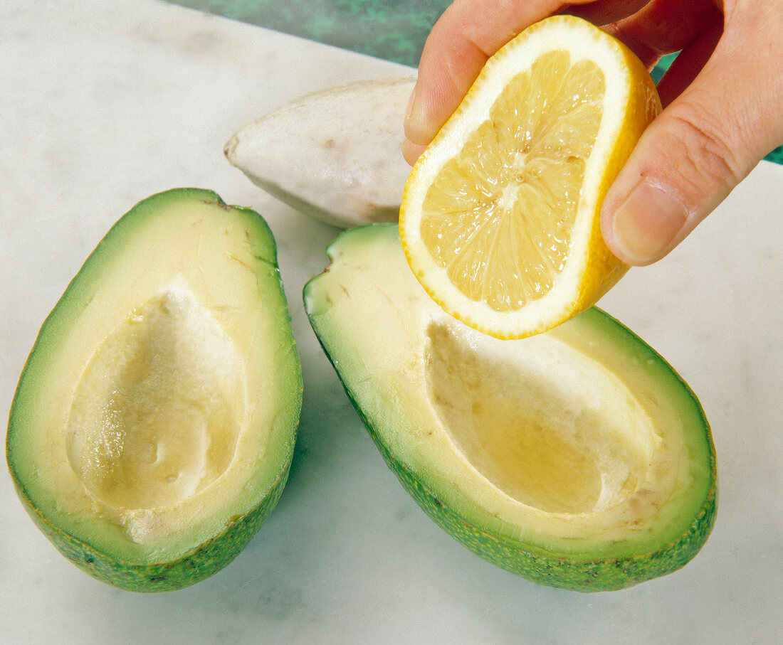 Close-up of half lemon being squeezed in avocado