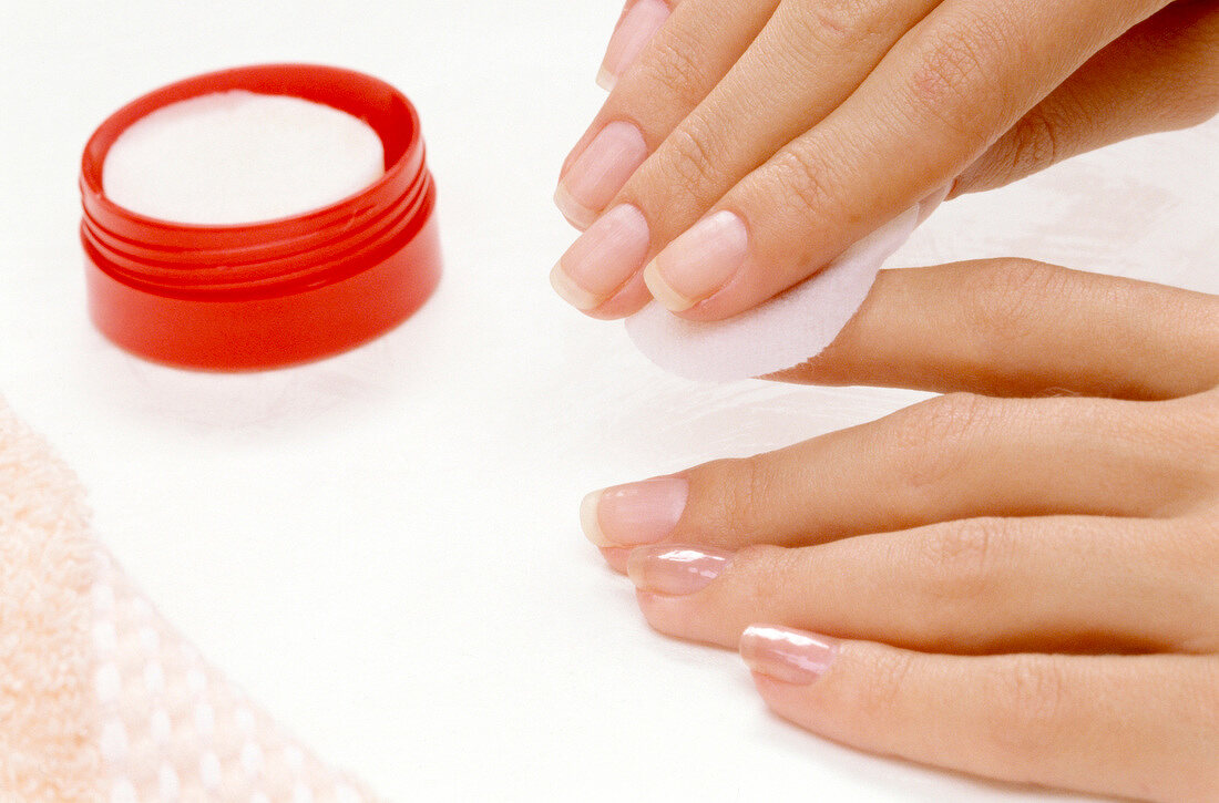 Close-up of woman removing nail polish with cotton pad