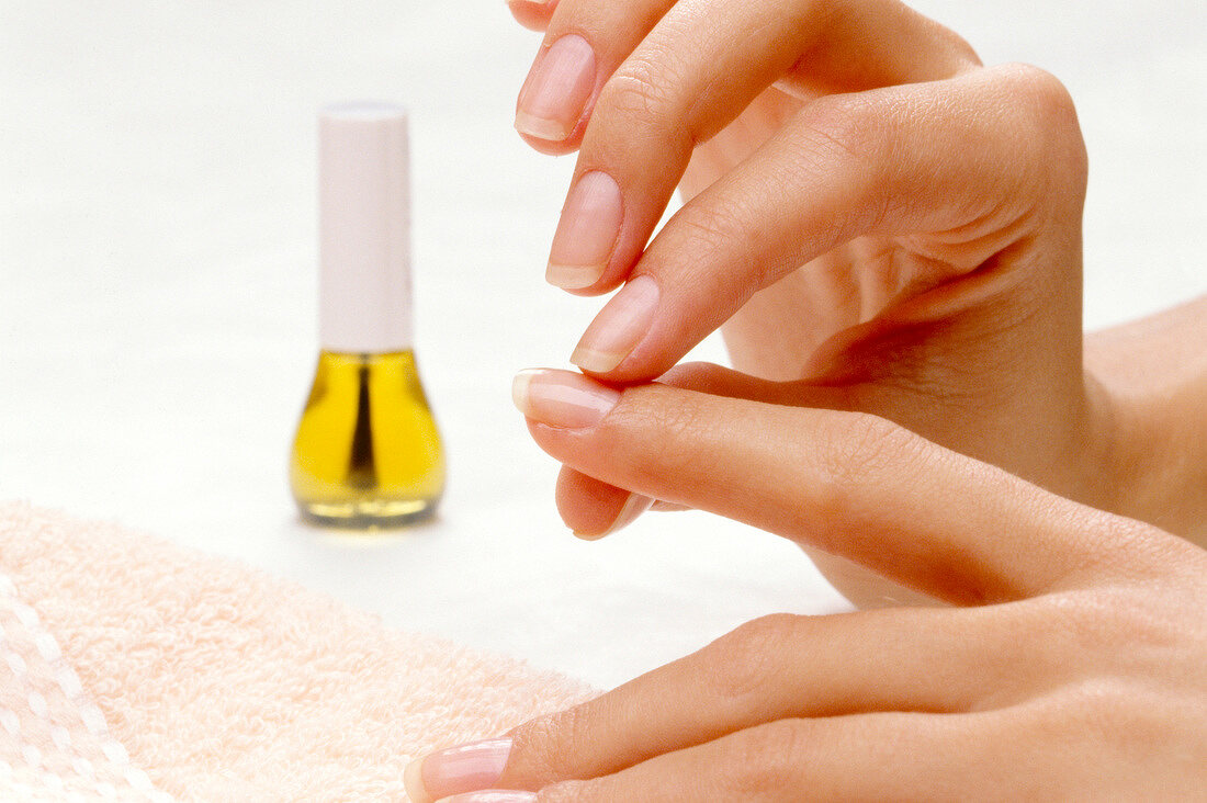 Close-up of woman applying nail oil on her fingernails