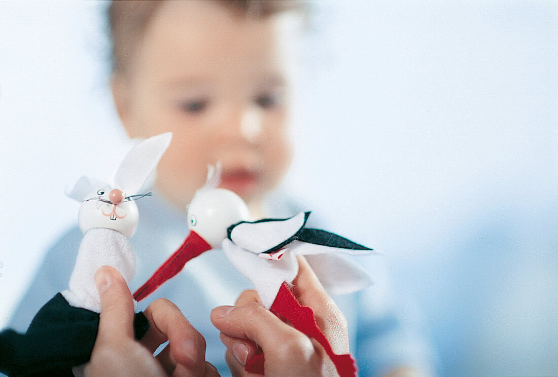 Baby. Wellness, Kleines Mädchen blickt auf zwei Fingerpuppen