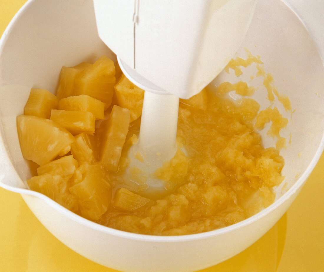 Pineapple pieces crushed with blender in bowl