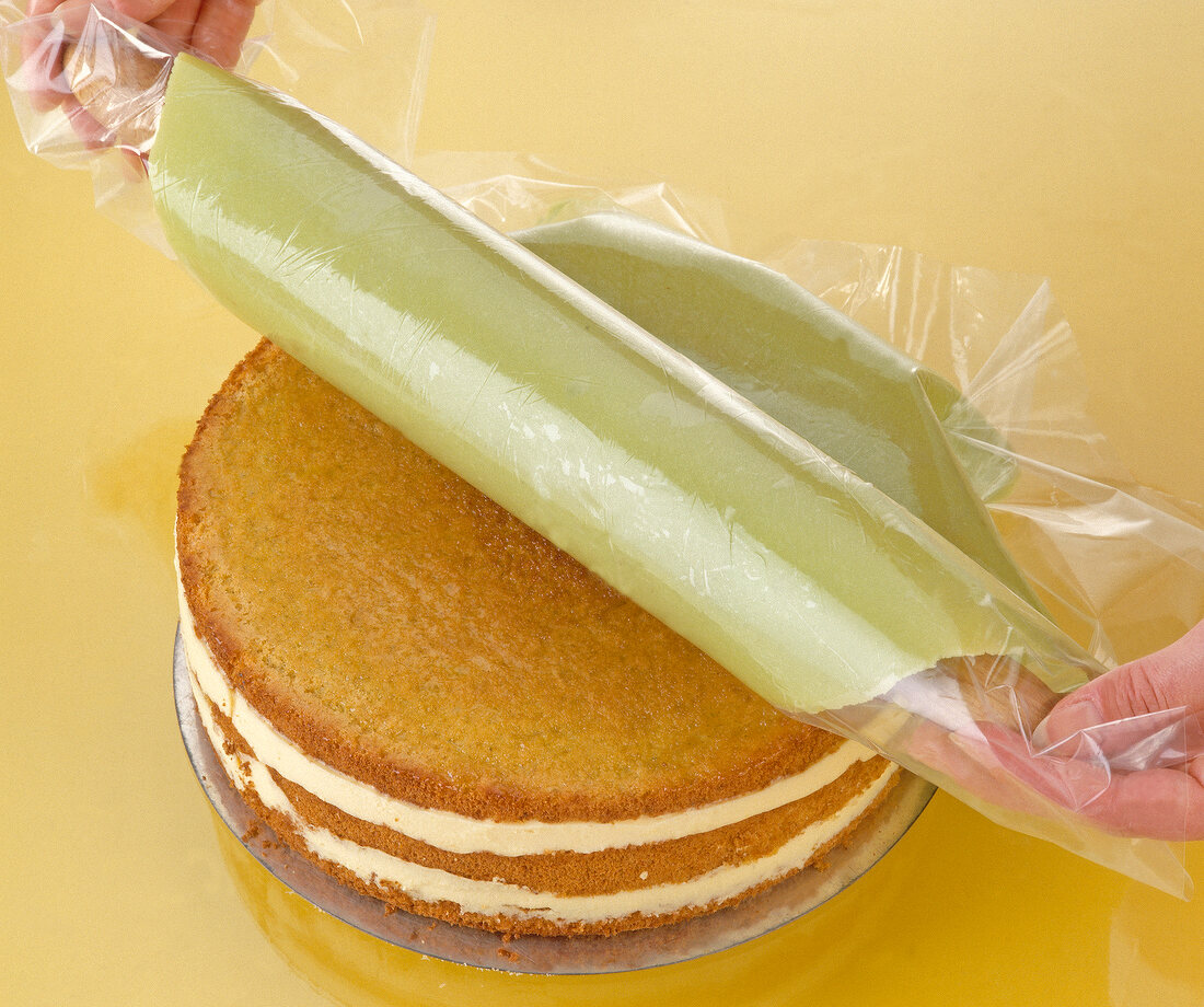 Green dough covered on layered Easter cake using plastic foil