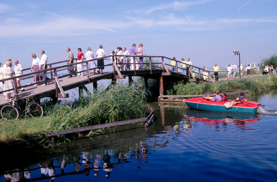 Tourists on wooden bridge and paddle boat, Steinhude, Germany