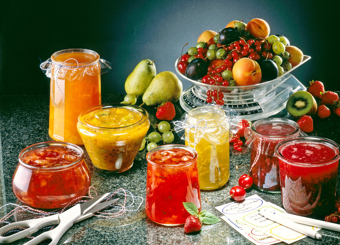 Variety of jams in glasses and fruits on a weighing scale