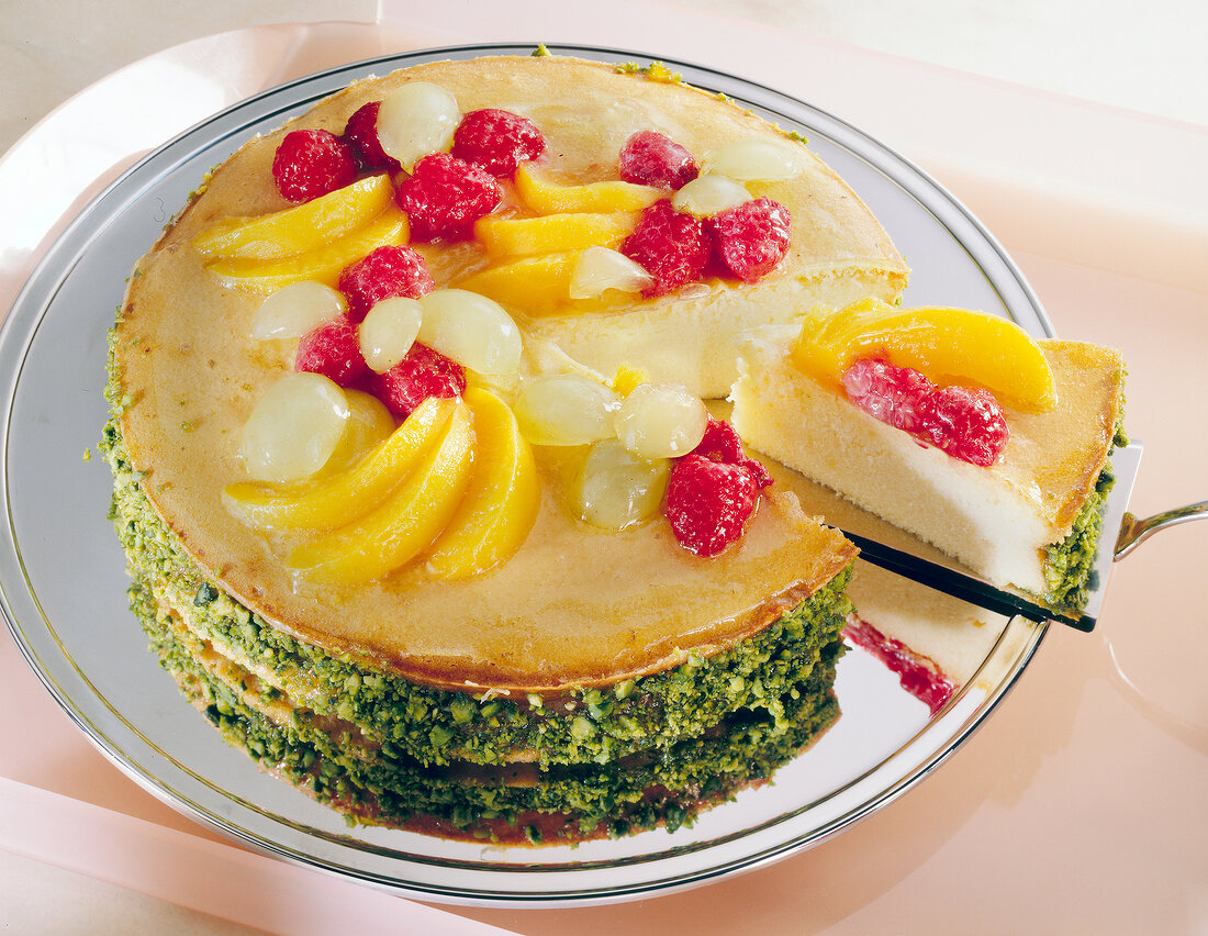 Close-up of cheesecake topped with various fruits and pistachios border