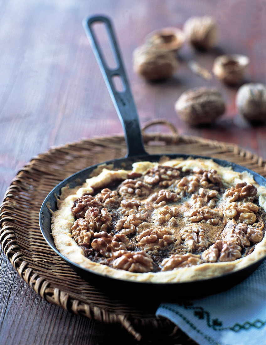 Walnut whiskey tart in a pan on cane table mat