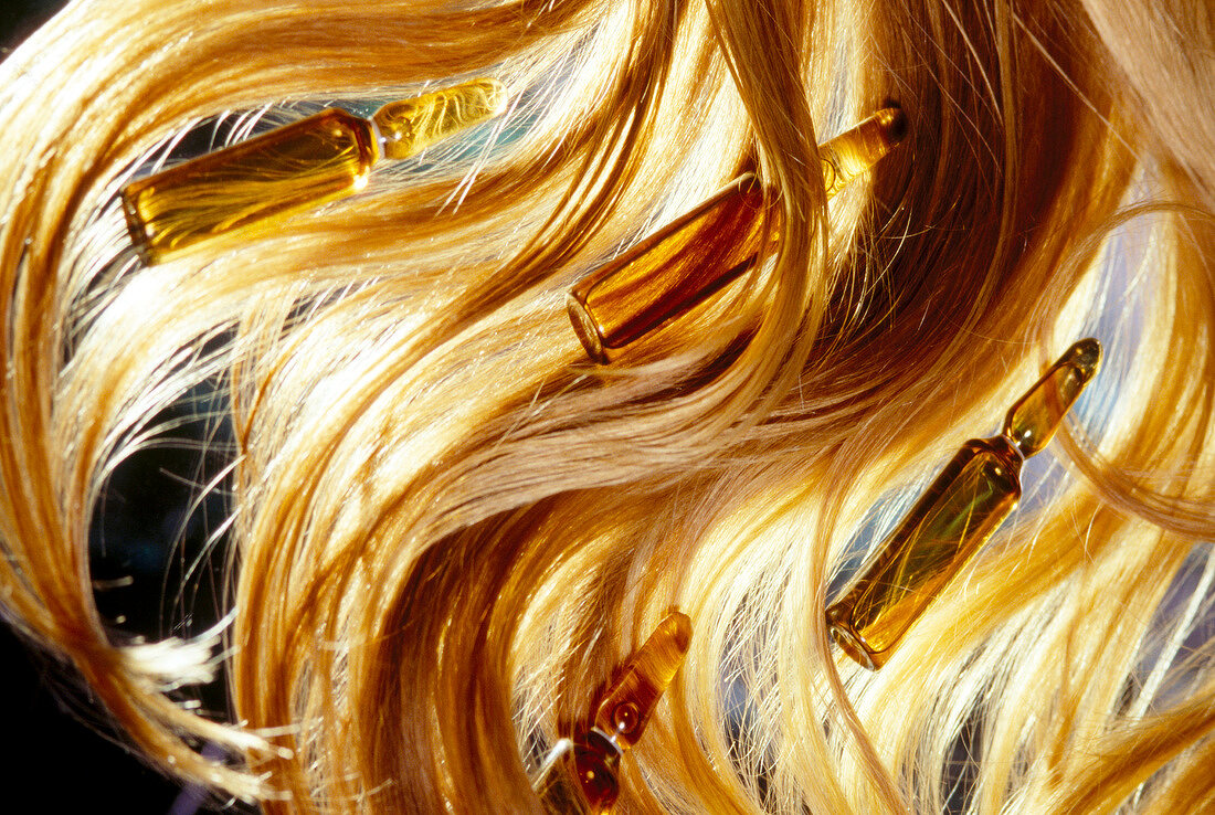 Close-up of ampoules in red hair strands symbolizing hair care