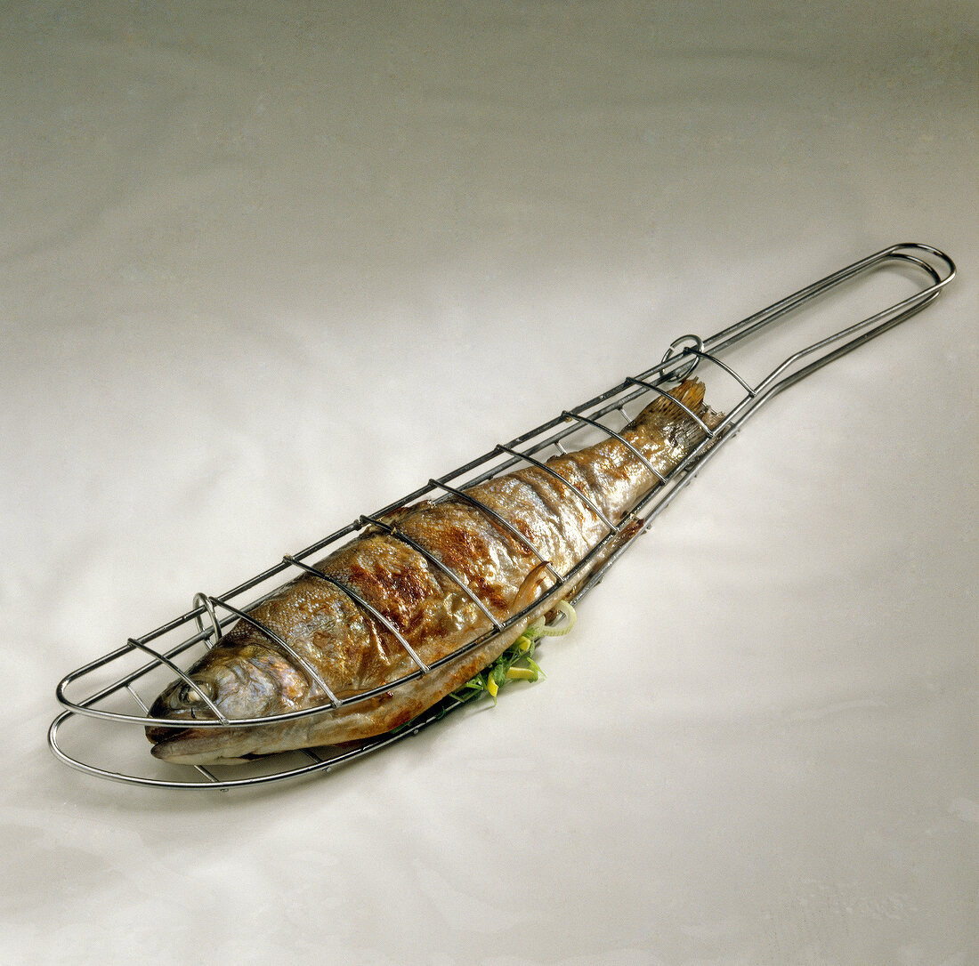 Gegrillte Forelle gefüllt mit Porree und Kräutern in Metall-Fischbräter