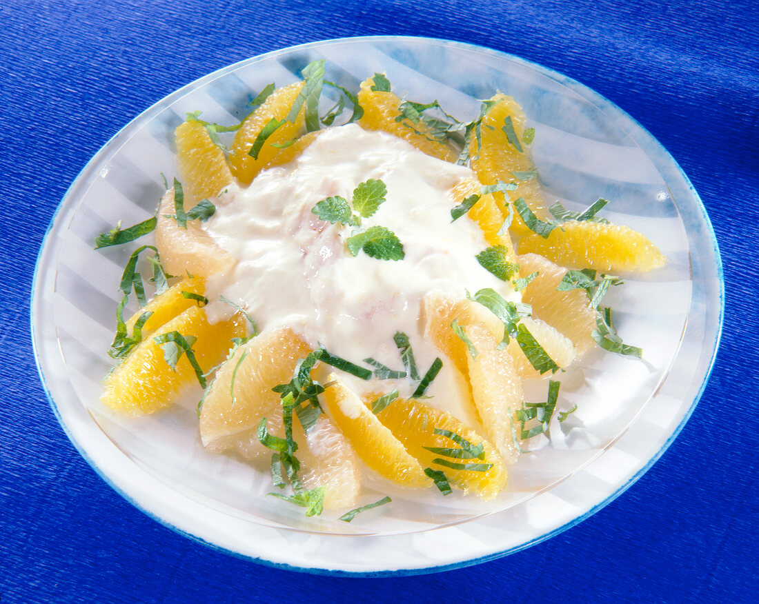 Close-up of grapefruit and orange salad with yogurt and lemon balm leaves