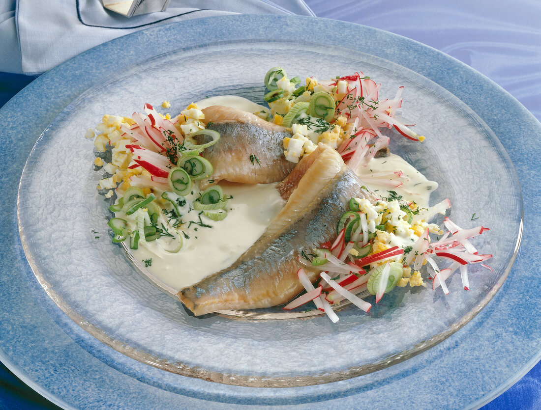 Close-up of herring fillets with egg and radish sauce on plate