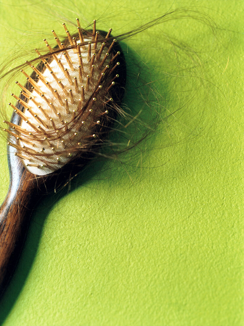 Hair brush with hair in it against green background