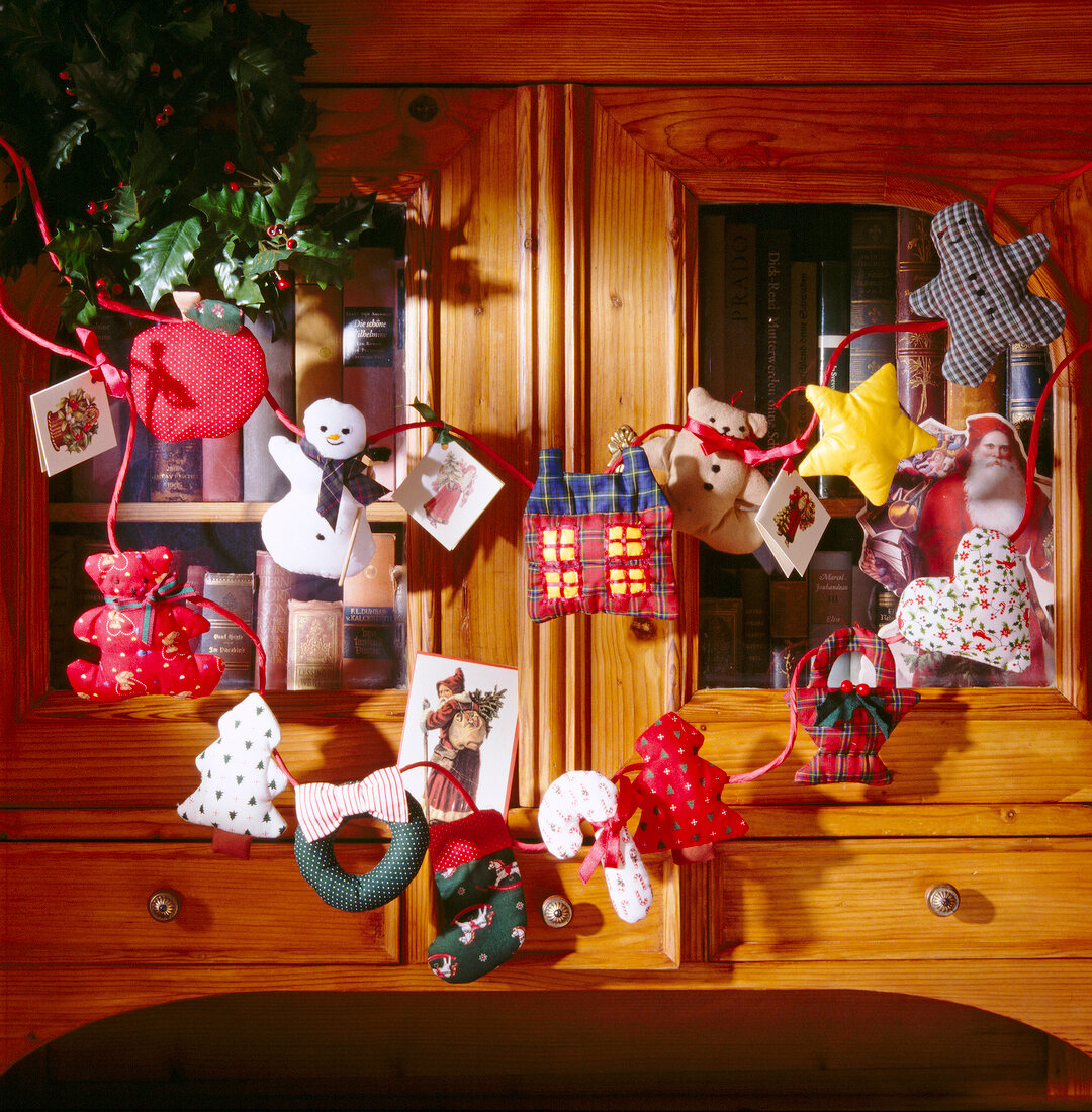 Girlande aus weihnachtlichen Stoff- figuren am Schrank