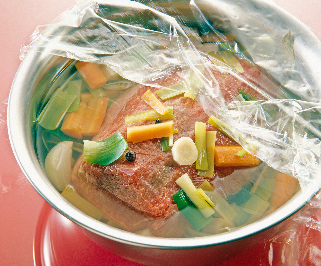 Meat and vegetable marinade in a bowl covered with plastic foil