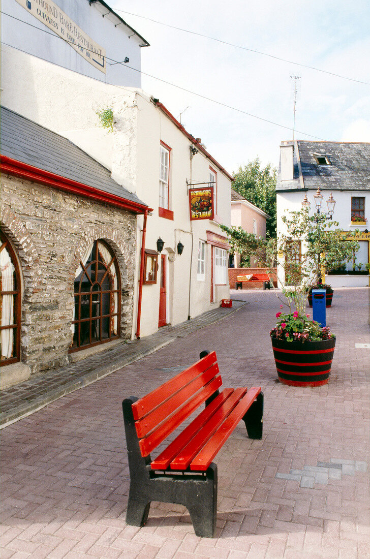 Blick auf eine Häuserfront mit einer roten Bank in Kinsale, Irland