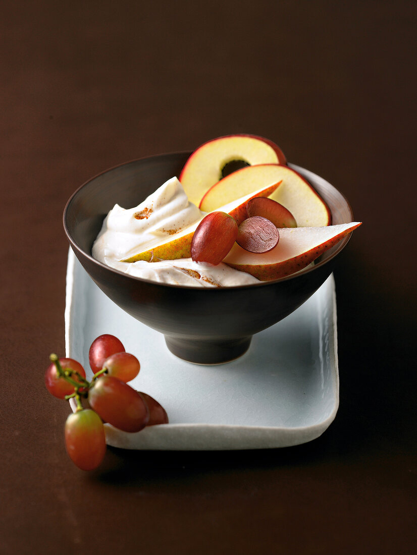 Cinnamon quark with apple slices and grapes in brown bowl