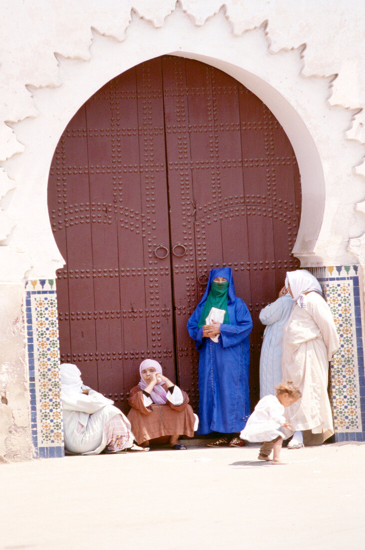 Frauen und Kinder stehen vor einer Moschee am Djemaa-el-Fna-Platz