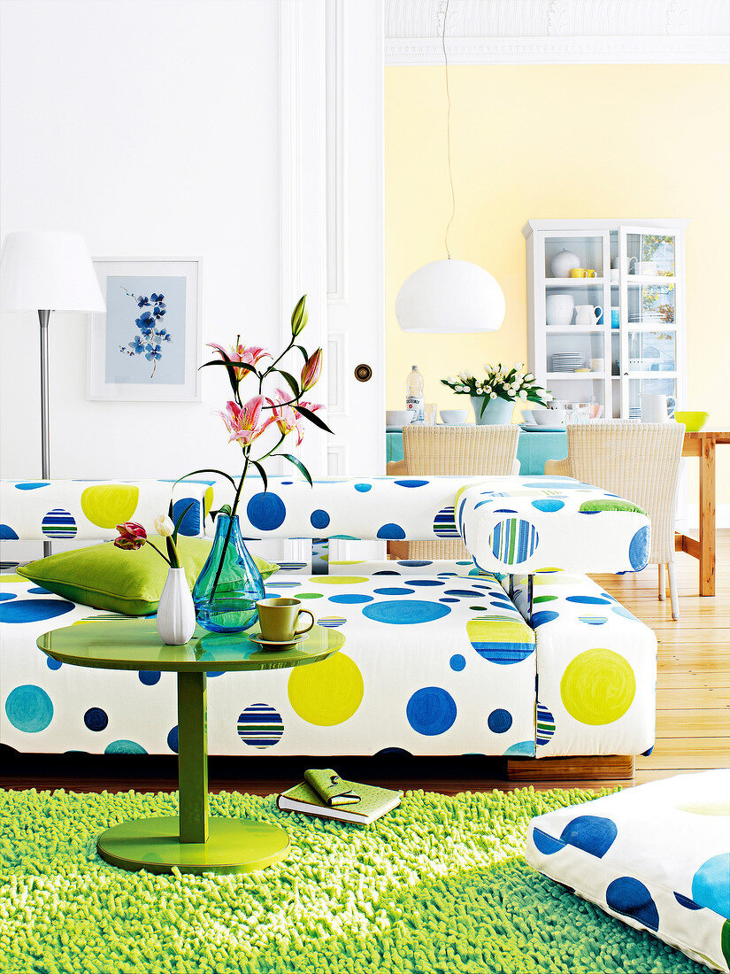 Living room with circle pattern white sofa, dining room in background