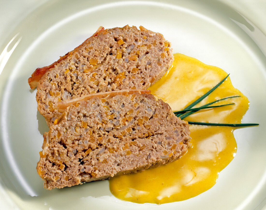 Two pieces of meatloaf with carrots, bean sprouts and curry sauce on plate