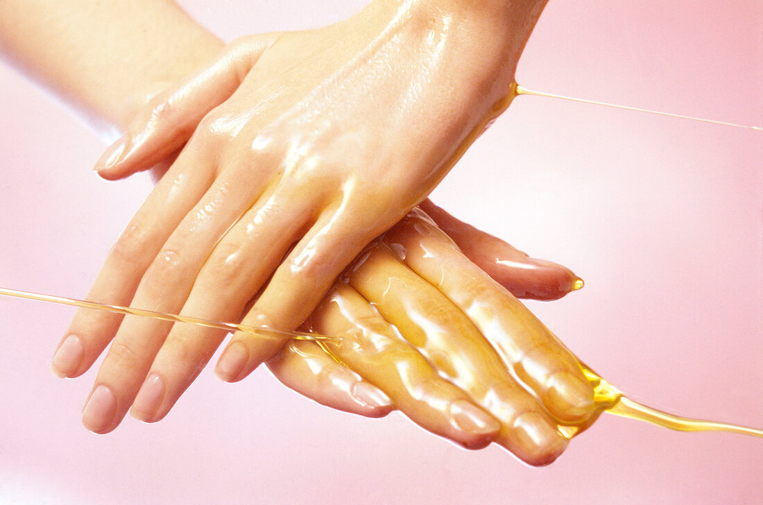 Close-up of woman's hand rubbing themselves with olive oil