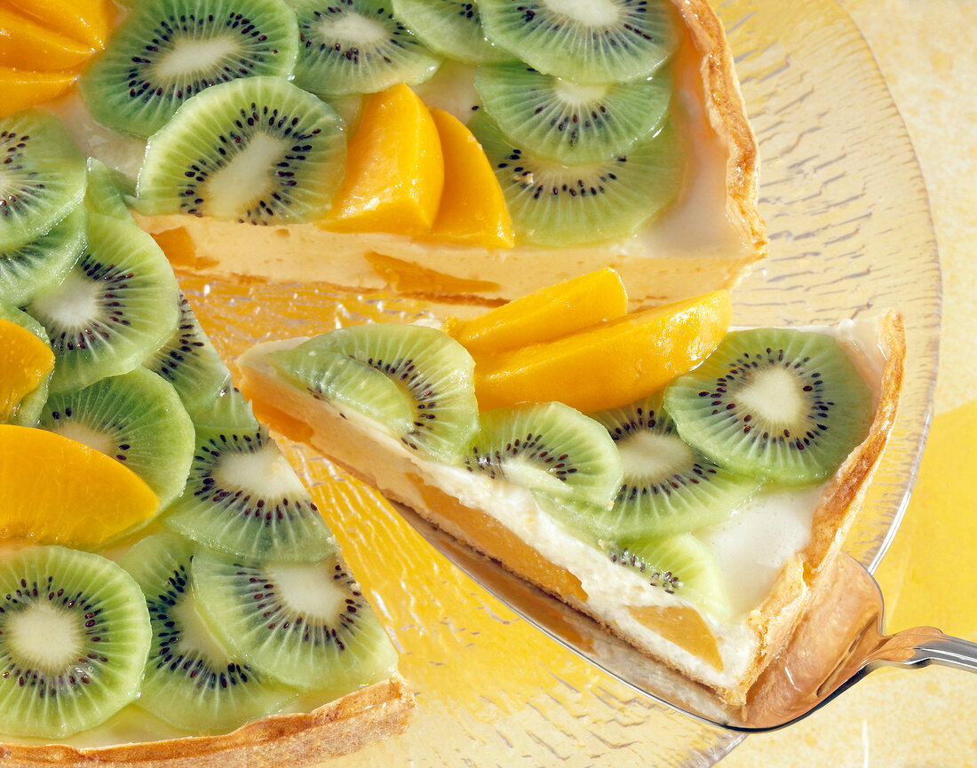 Close-up of kiwi peach cake with slice of cake on spatula
