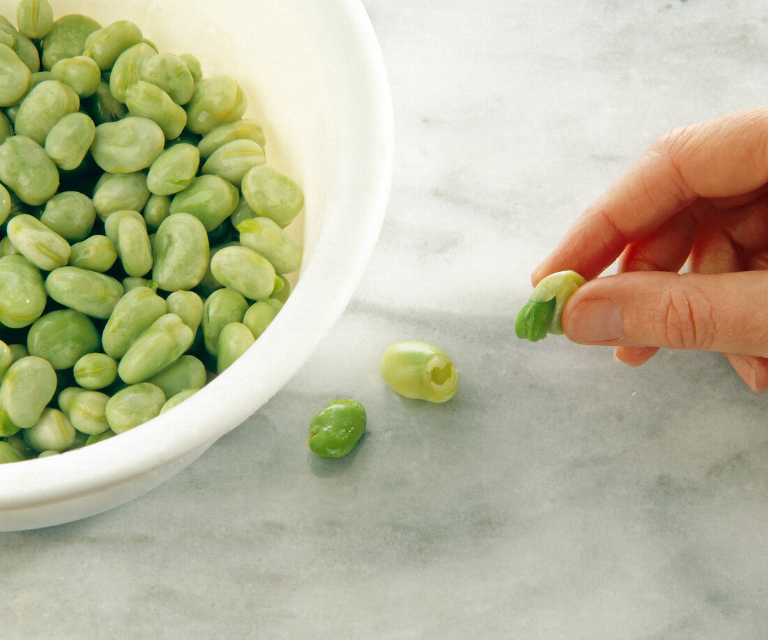 Close-up of woman's hand pressing out seeds from green beans