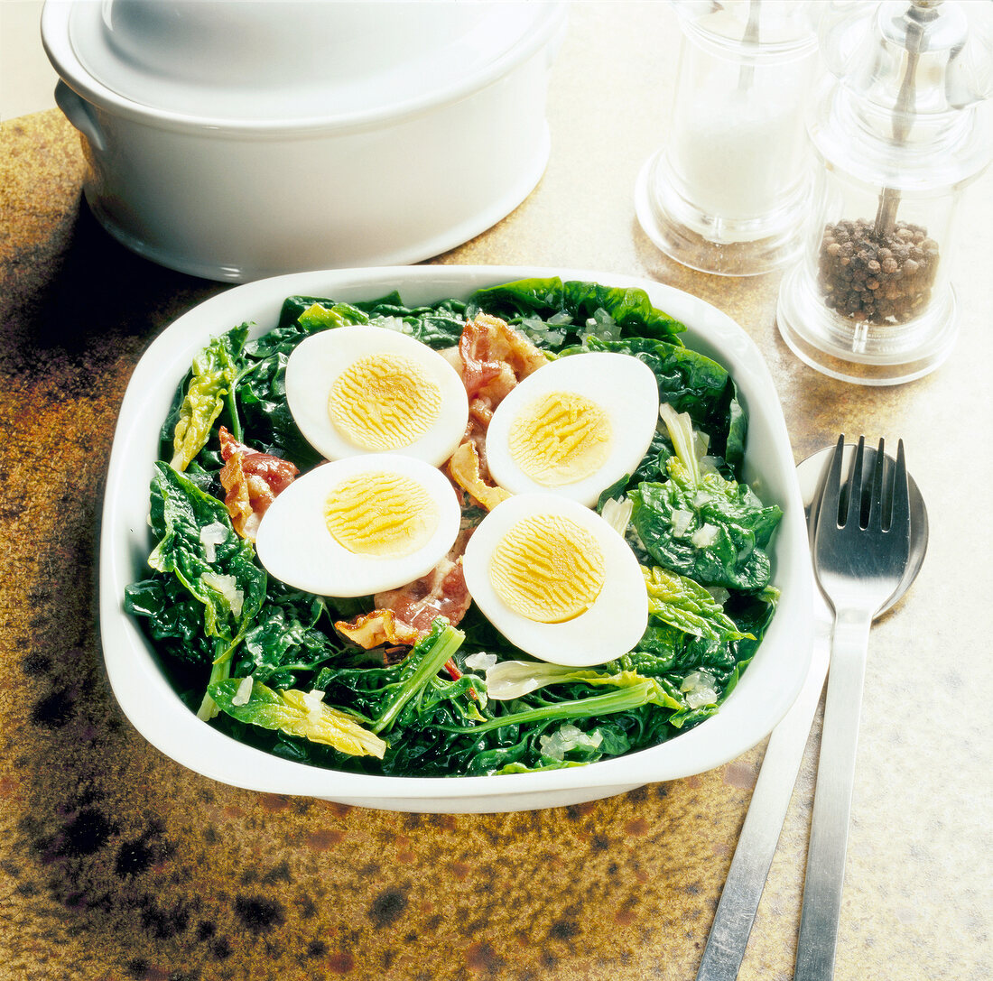 Bowl of spinach with bacon and boiled eggs
