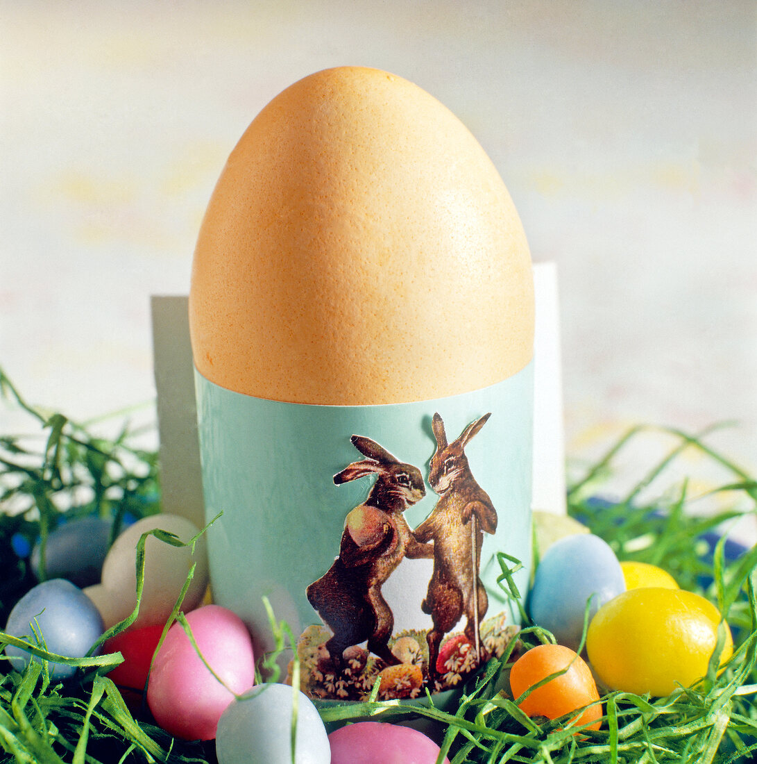 Close-up of Easter egg in green egg cups decorated with Easter image