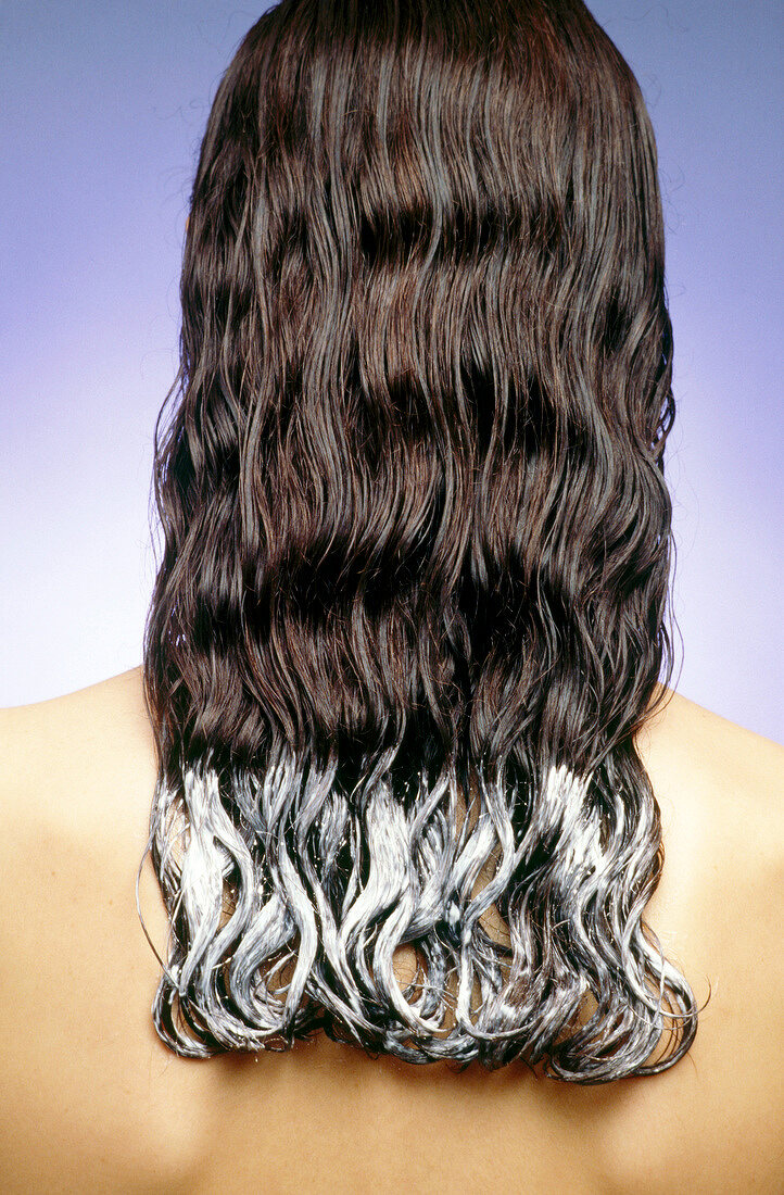 Rear view of woman with burdock root oil on tips of her long hair