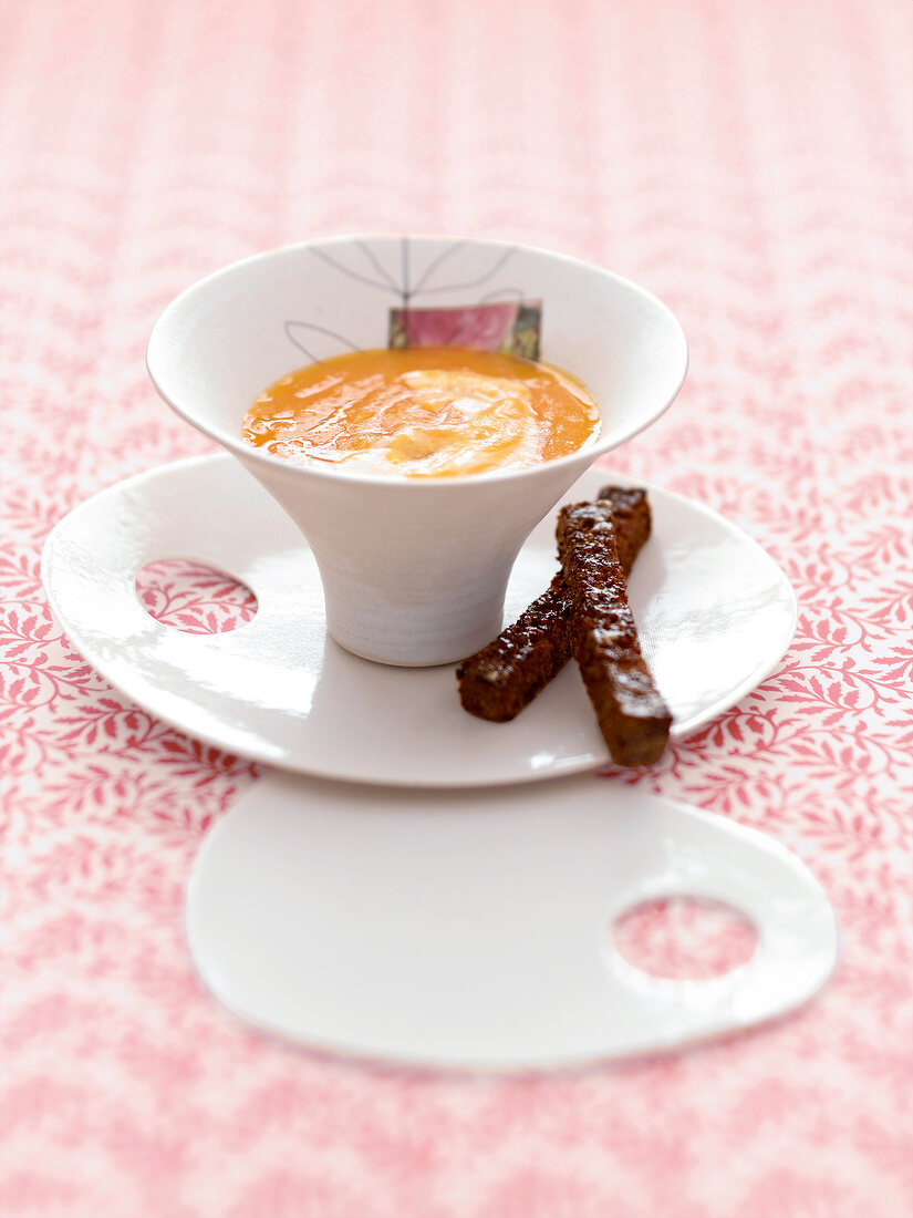 Bowl of carrot and apple soup with cinnamon croutons on plate